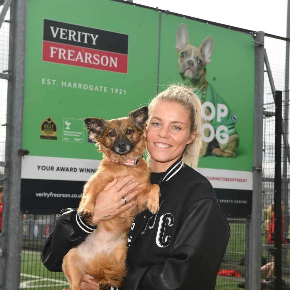 Lioness Rachel Daly and her dog Dexi posing infront of a sign saying Top Dog